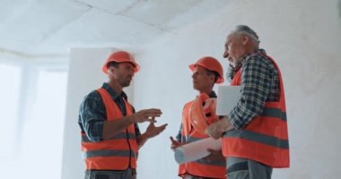 İnşaat alanında konuşan dijital tabletli ve planlı inşaatçılar