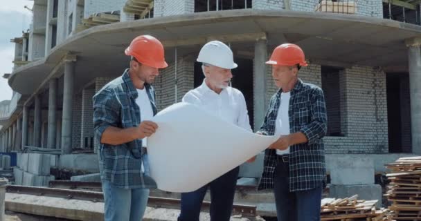 工程师及建筑商讨论建筑工地蓝图 — 图库视频影像