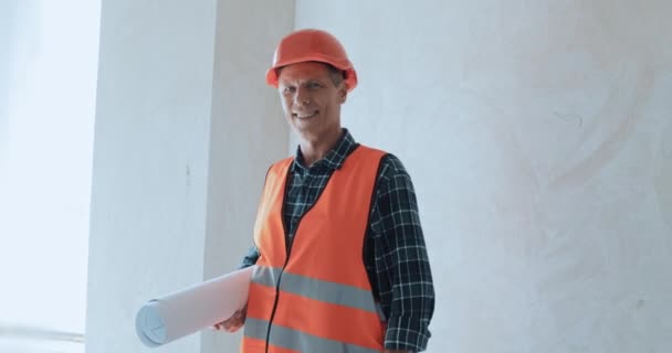 Uśmiechnięty Budowniczy Trzymający Plan Patrzący Kamerę Placu Budowy — Wideo stockowe