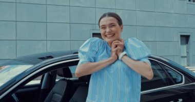 Mutlu, heyecanlı kadın zıplıyor, arabanın anahtarını gösteriyor ve kendi arabasını kucaklıyor.