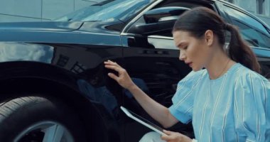 ciddi bir kadın arabaya dokunuyor ve dijital tablet kullanıyor