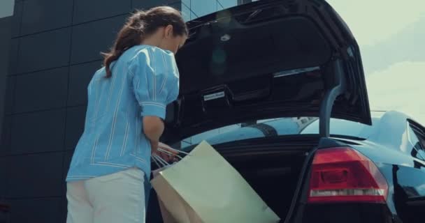 Glückliche Frau Nimmt Einkaufstüten Aus Dem Kofferraum — Stockvideo