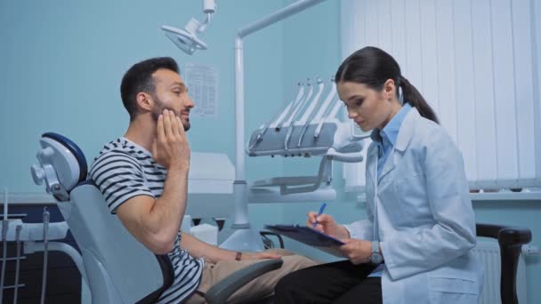 Ασθενής Κάνει Χειρονομίες Ενώ Μιλάει Στον Οδοντίατρο Πρόχειρο Στην Κλινική — Αρχείο Βίντεο