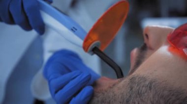 Klinikte hastayla çalışırken diş macunu kullanan diş hekimi 