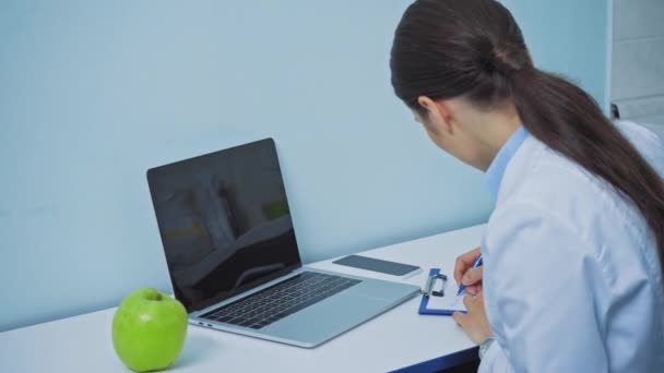 Dentista Che Usa Laptop Scrive Sugli Appunti Vicino Alla Mela — Video Stock