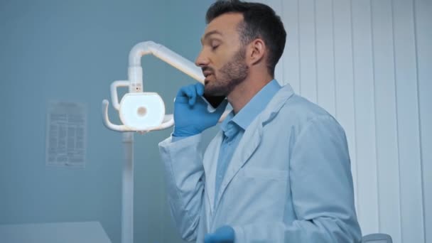 Όμορφος Οδοντίατρος Μιλάει Στο Smartphone Στην Κλινική — Αρχείο Βίντεο
