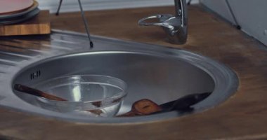 Mutfak lavabosuna sofra takımı koyan adamın kırpılmış görüntüsü 