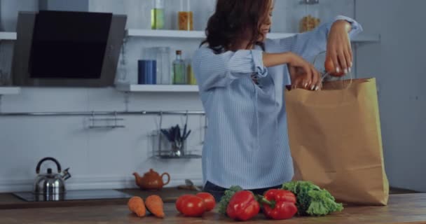 Mujer Joven Poniendo Verduras Orgánicas Bolsa Papel Mesa Cocina — Vídeos de Stock