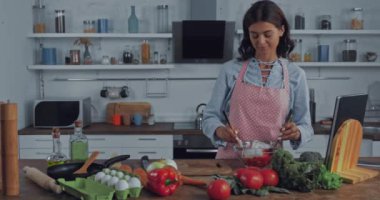 Mutfakta olgun sebzelerin yanında salata karıştıran kadın. 