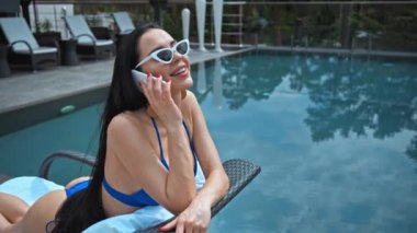 Güneş gözlüklü ve bilardo masasında konuşan genç bir kadın.