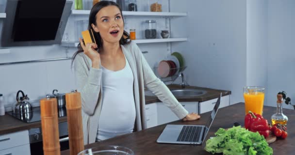 在厨房里 孕妇在桌上的蔬菜旁使用信用卡和笔记本电脑 — 图库视频影像