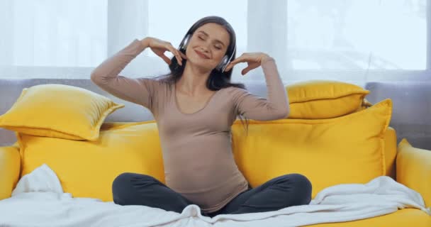 妊婦リッスン音楽でヘッドフォンオンソファ — ストック動画