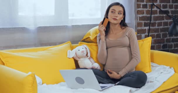 妊婦用ラップトップとクレジットカードを使用してソファ — ストック動画