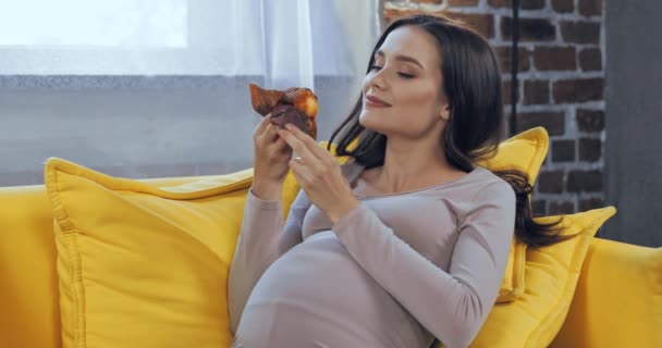 妊婦食べるカップケーキオンソファ — ストック動画