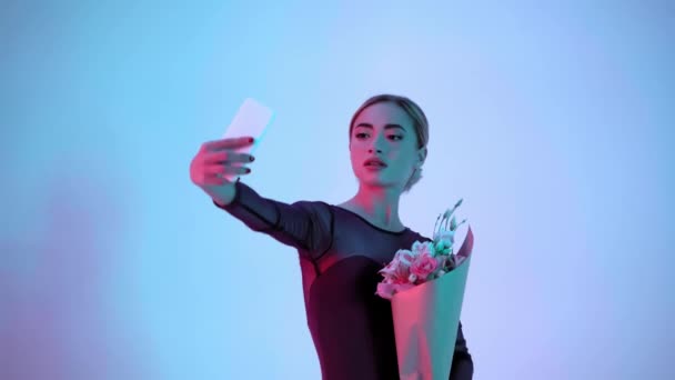 年轻的芭蕾舞演员带着蓝色和粉色背景的花自拍 — 图库视频影像