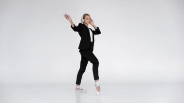 Genç balerin müzik dinliyor ve beyaz arka planda dans ediyor.