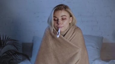 Hasta kadının dijital termometreyi ağzında tuttuğu raflar. İlacın yanında.