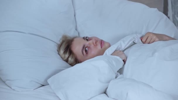 Незадоволена Жінка Прикриває Вуха Лежачи Під Ковдрою Ліжку — стокове відео