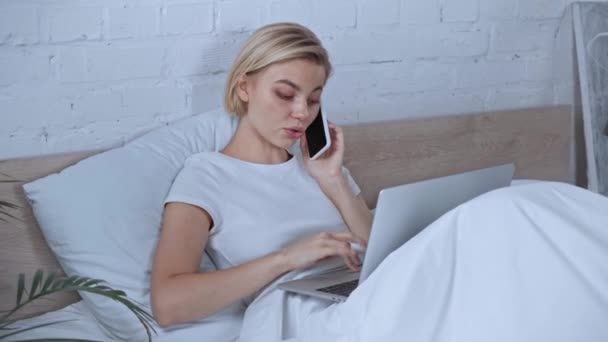 Rubia Freelancer Hablando Smartphone Cerca Del Ordenador Portátil Dormitorio — Vídeos de Stock