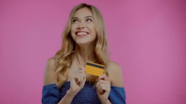 Heyecanlı sarışın kadın mor üzerine izole edilmiş kredi kartı gösteriyor.