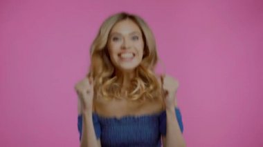 Heyecanlı sarışın kadın dans ediyor ve evet işareti yapıyor mor renkte izole edilmiş.