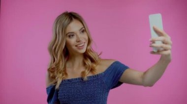 Sarışın kadın selfie çekiyor ve baş parmağını mor renkte gösteriyor.