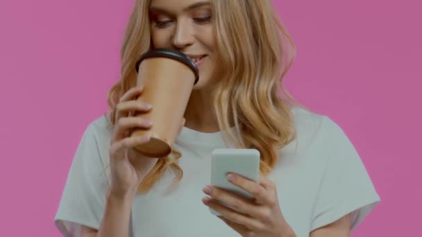 紫の上に隔離されたスマートフォンや飲酒コーヒーを使用して高価なブロンドの女性 — ストック動画