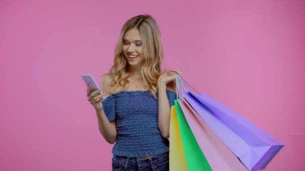 Blonde Woman Shopping Bags Using Smartphone Isolated Purple — Stock Video