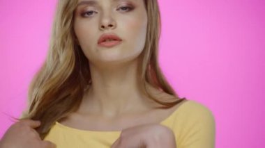 Yüzüne dokunan genç bir kadının portresi Pembe üzerinde yalnız poz verirken