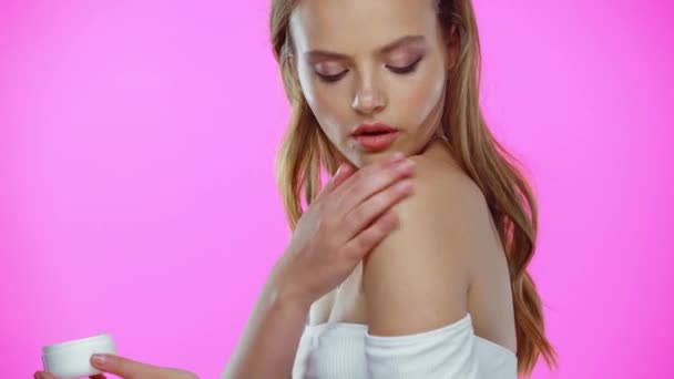 Ung Kvinna Applicera Kosmetisk Kräm Axeln Isolerad Rosa — Stockvideo