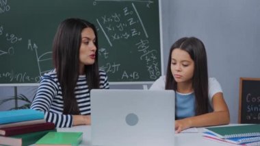 Anne laptopun yanında çocukla konuşurken ev ödevlerini anlatıyor. 