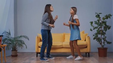 Anne ve kızı evde eğleniyor ve dans ediyor.