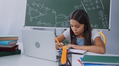 Evde internetten okurken kulaklık takan heyecanlı öğrenci.