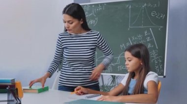 Hüzünlü annenin elinde kitap tutması ve üzgün çocuğun yanındaki defterden kağıt yırtması.