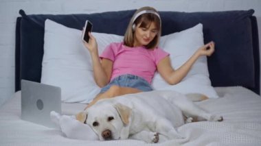 Kulaklıklı bir kadının yanında müzik dinleyen bir köpeğin seçici odağı.