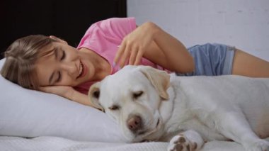 Mutlu kadın yastığa uzanıyor ve Golden Retriever 'a sarılıyor.