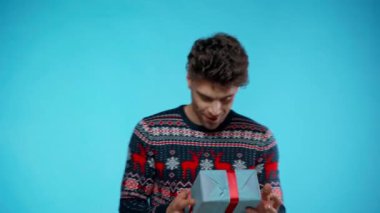 Heyecanlı genç bir adam mavi ışıkta hediye yakalıyor.