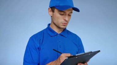 Kapşonlu teslimatçı panoya yazı yazıyor ve gri üzerine gülümsüyor.