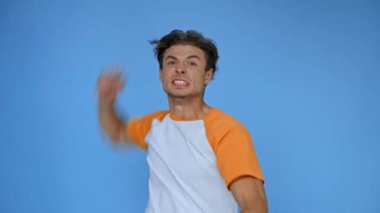 Yumruğunu sıkmış kızgın bir adam mavi üzerine izole edilmiş kameraya bakıyor.