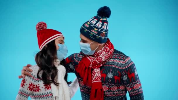 Unga Par Varma Kläder Och Medicinska Masker Omfamna Blå — Stockvideo