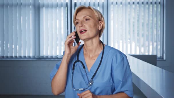 Blond Och Medelålders Läkare Talar Smartphone Kliniken — Stockvideo