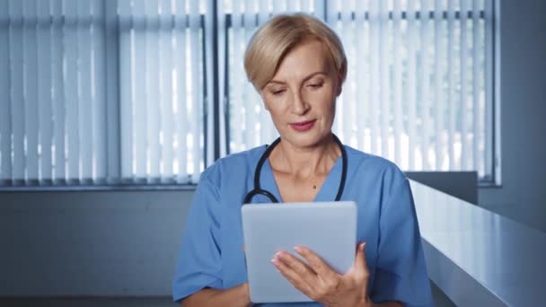 Médico Mediana Edad Usando Tableta Digital Sonriendo Mientras Mira Hacia — Vídeo de stock