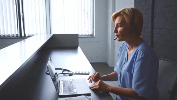 Dokter Paruh Baya Dalam Konsultasi Headset Online Dekat Laptop Klinik — Stok Video