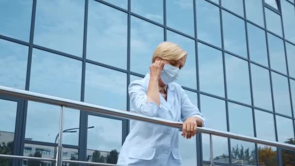 Втомлений Середнього Віку Лікар Знімає Медичну Маску Біля Скляного Фасаду — стокове відео