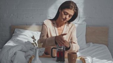 Esmer kadın sabahları yatağında çay içiyor.