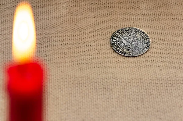 Ancient silver coin and burning candle — Stock Photo, Image