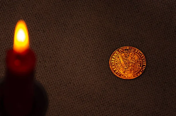 Ancient silver coin and burning candle — Stock Photo, Image