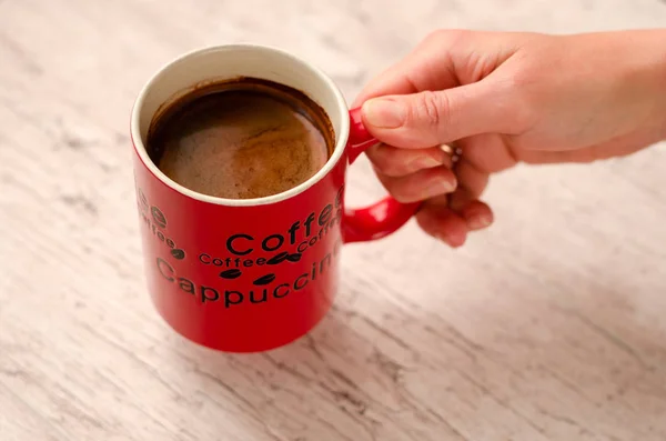 Female hand holding a mug of coffee on wooden background — Stock Photo, Image