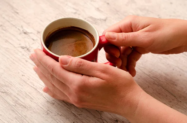 Mains féminines tenant une tasse de café sur fond en bois — Photo