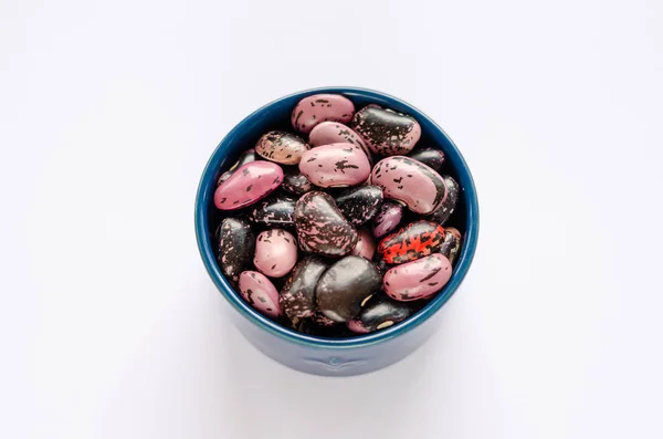 Чаша різнокольорових сушених бобів на білому тлі — стокове фото